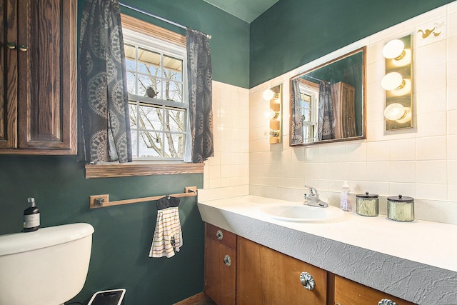 bathroom featuring toilet, vanity, and backsplash