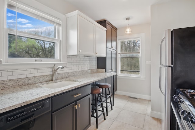 kitchen with tasteful backsplash, a sink, light tile patterned flooring, baseboards, and appliances with stainless steel finishes