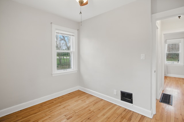spare room featuring light wood-type flooring, visible vents, and baseboards