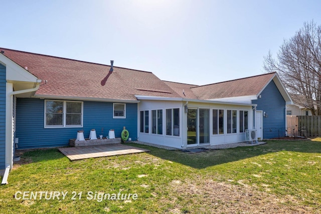 back of house with a yard, fence, a sunroom, and roof with shingles