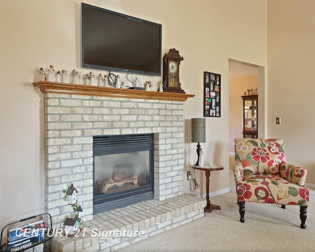 living area featuring carpet floors, baseboards, and a brick fireplace