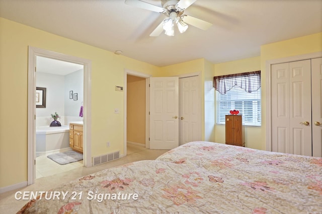 bedroom featuring two closets, ensuite bathroom, baseboards, and visible vents