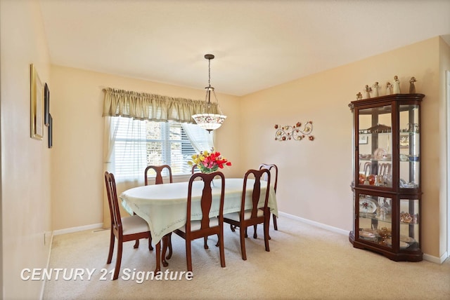 carpeted dining area with an inviting chandelier and baseboards