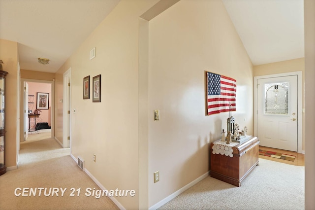 hallway featuring baseboards, carpet, visible vents, and lofted ceiling