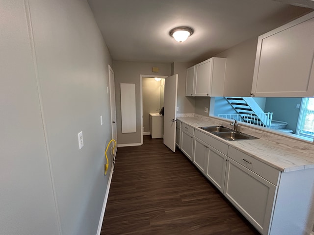 kitchen featuring baseboards, dark wood-type flooring, light countertops, and a sink