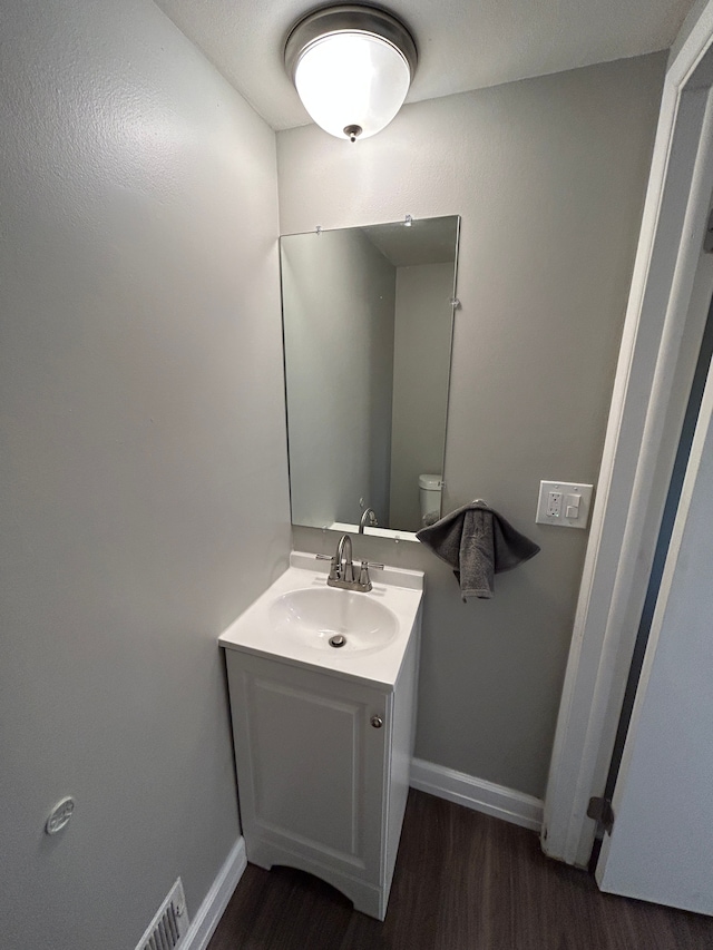 bathroom featuring vanity, baseboards, visible vents, and wood finished floors
