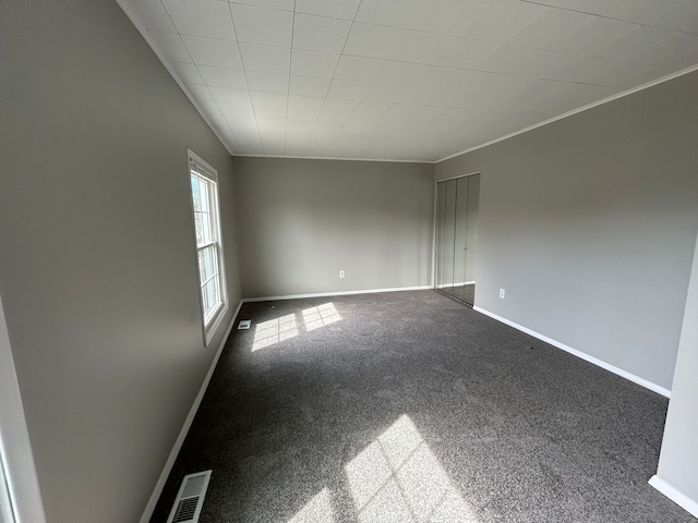 spare room featuring crown molding, visible vents, baseboards, and carpet flooring