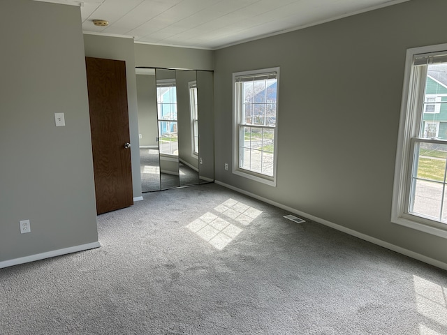spare room featuring carpet flooring, baseboards, ornamental molding, and visible vents