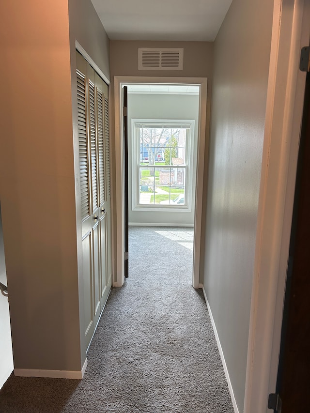 hallway featuring carpet flooring, baseboards, and visible vents