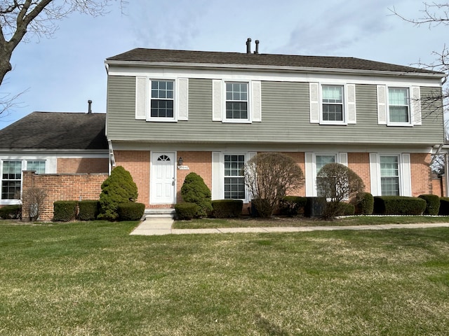 colonial house with a front yard and brick siding