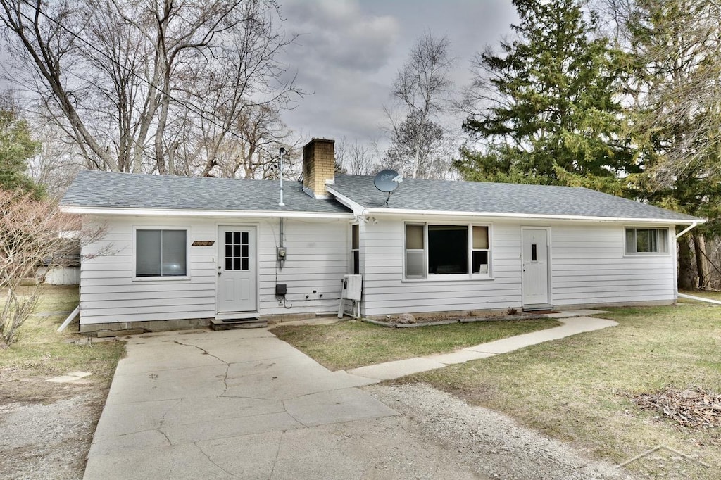5700 N Saginaw Rd, Midland, MI 48640 - rear view of house featuring a yard, driveway, a chimney, and a shingled roof