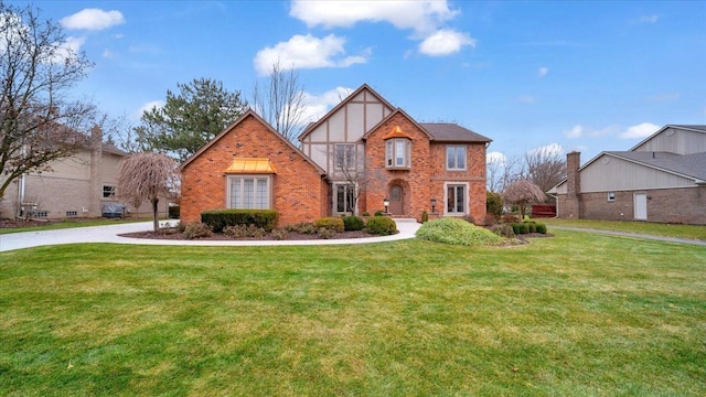 tudor home with a front lawn and brick siding