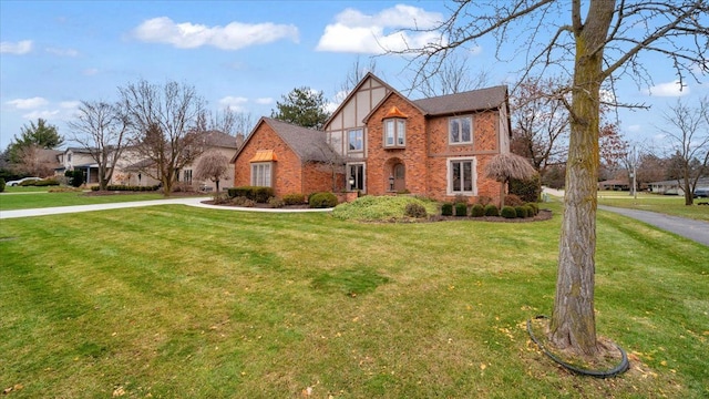 tudor house featuring a front lawn and brick siding