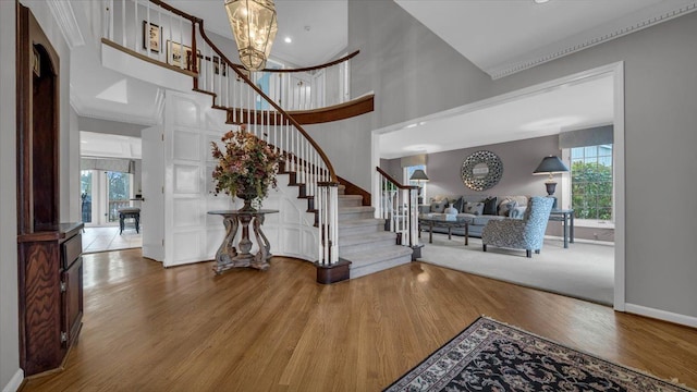 entryway featuring a towering ceiling, baseboards, wood finished floors, and stairs