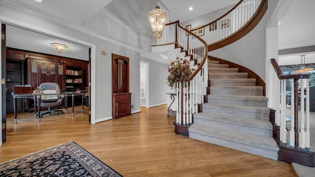 entryway featuring stairway, a high ceiling, wood finished floors, crown molding, and baseboards