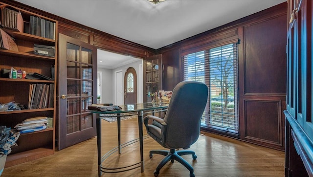 office featuring wood finished floors, french doors, built in features, and ornamental molding