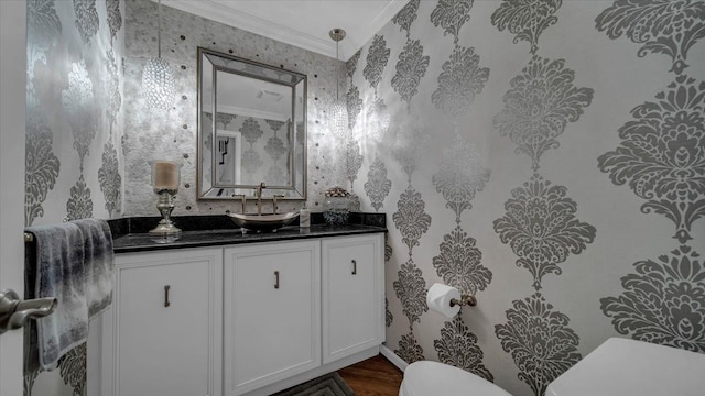half bathroom featuring wallpapered walls, wood finished floors, toilet, vanity, and crown molding