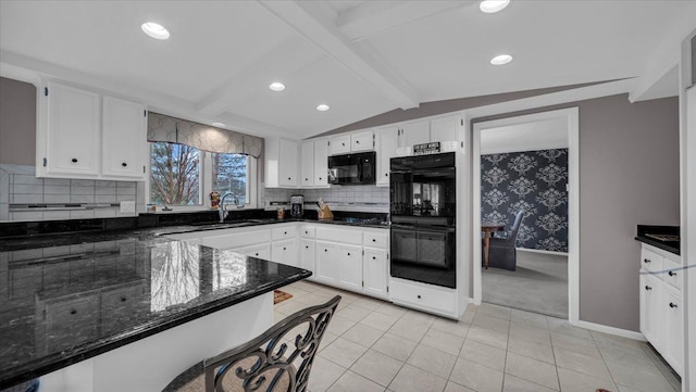 kitchen featuring dark stone counters, a sink, black appliances, lofted ceiling with beams, and white cabinetry