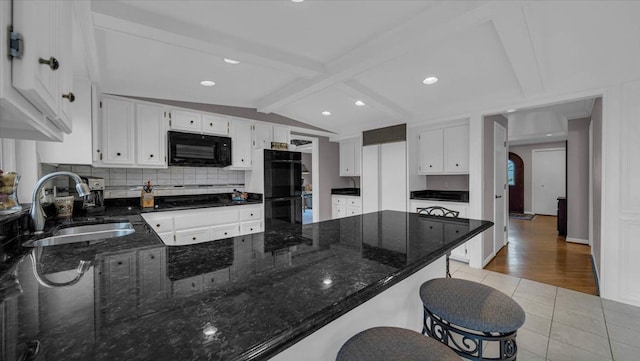 kitchen featuring a sink, black appliances, decorative backsplash, light tile patterned flooring, and a peninsula