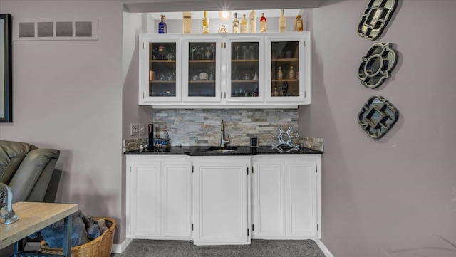 bar with visible vents, a sink, baseboards, tasteful backsplash, and indoor wet bar