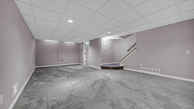 finished basement with baseboards, a paneled ceiling, visible vents, and carpet