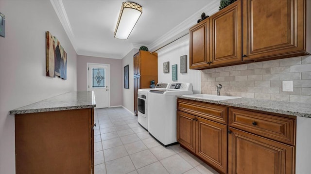 laundry room featuring a sink, light tile patterned flooring, cabinet space, washing machine and dryer, and ornamental molding