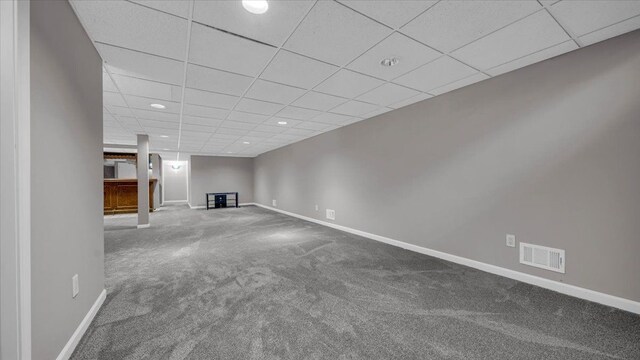 finished below grade area featuring baseboards, carpet floors, visible vents, and a paneled ceiling