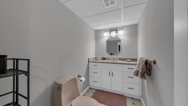 bathroom featuring a paneled ceiling, toilet, baseboards, visible vents, and vanity
