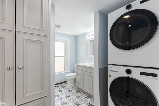 bathroom featuring vanity, visible vents, toilet, and stacked washer and clothes dryer
