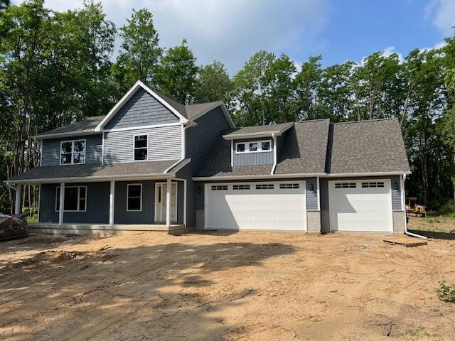 2035 Dakota Trl, Hastings, MI 49058 - view of front of house featuring an attached garage, a porch, driveway, and view of scattered trees