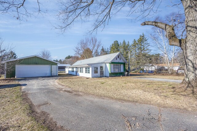 6313 Fairlane Dr, Lake City, MI 49651 - view of front of house with an outbuilding, a front yard, a detached garage, and metal roof