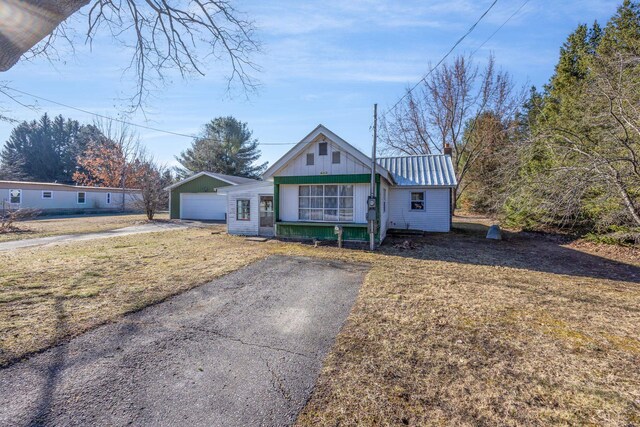 6313 Fairlane Dr, Lake City, MI 49651 - bungalow with aphalt driveway, a front lawn, a standing seam roof, a detached garage, and metal roof