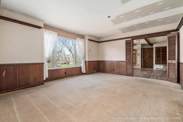 1220 W Green St, Hastings, MI 49058 - unfurnished room featuring wooden walls, wainscoting, visible vents, and carpet floors