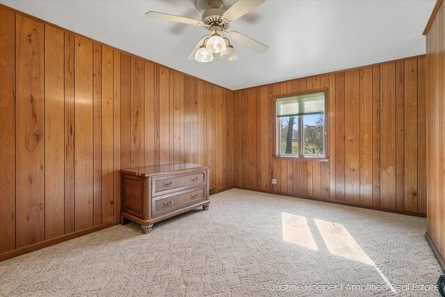 1220 W Green St, Hastings, MI 49058 - unfurnished bedroom with light carpet, wood walls, baseboards, and a ceiling fan