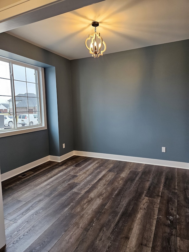 unfurnished room with an inviting chandelier, baseboards, dark wood finished floors, and visible vents