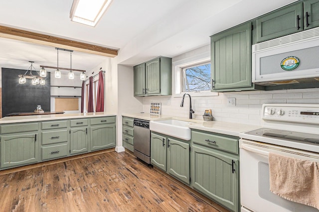 kitchen with white appliances, tasteful backsplash, green cabinets, light countertops, and a sink