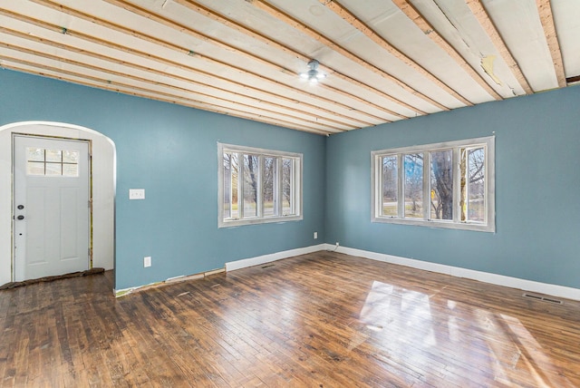 interior space featuring visible vents, baseboards, wood-type flooring, and arched walkways