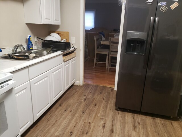 16115 Westbrook St, Detroit, MI 48219 - kitchen with white cabinetry, black fridge, white electric stove, light wood finished floors, and a sink