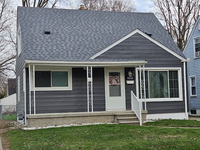 bungalow-style home featuring a shingled roof and a front yard
