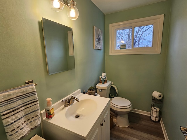 bathroom with baseboards, wood finished floors, toilet, and vanity