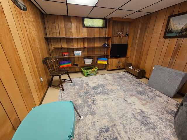 sitting room with a paneled ceiling and wooden walls