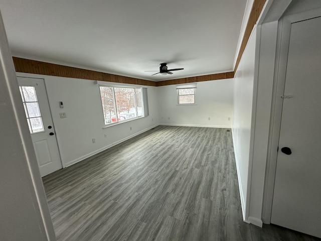 interior space with wood finished floors, ornamental molding, baseboards, and a ceiling fan