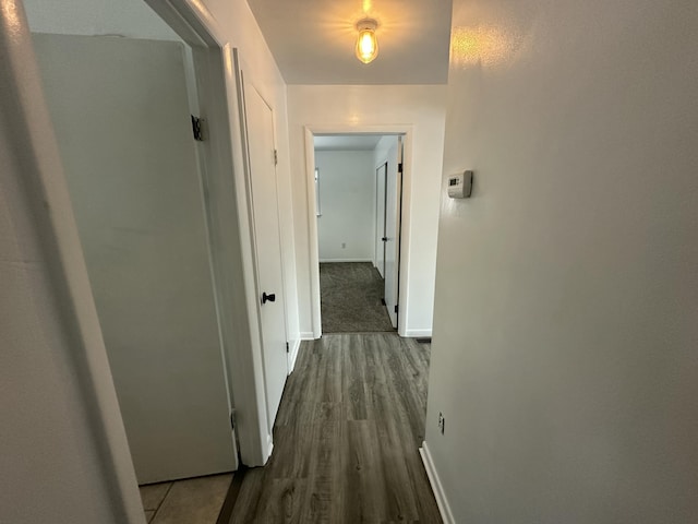 hall featuring dark wood-type flooring and baseboards