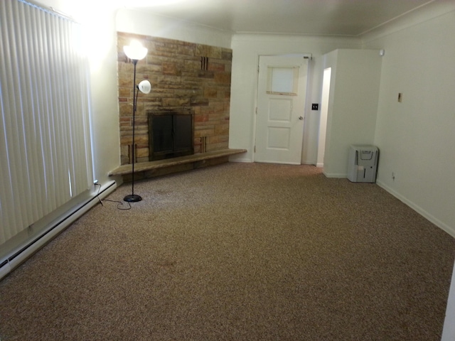 unfurnished living room with a fireplace, a baseboard heating unit, baseboards, and carpet floors