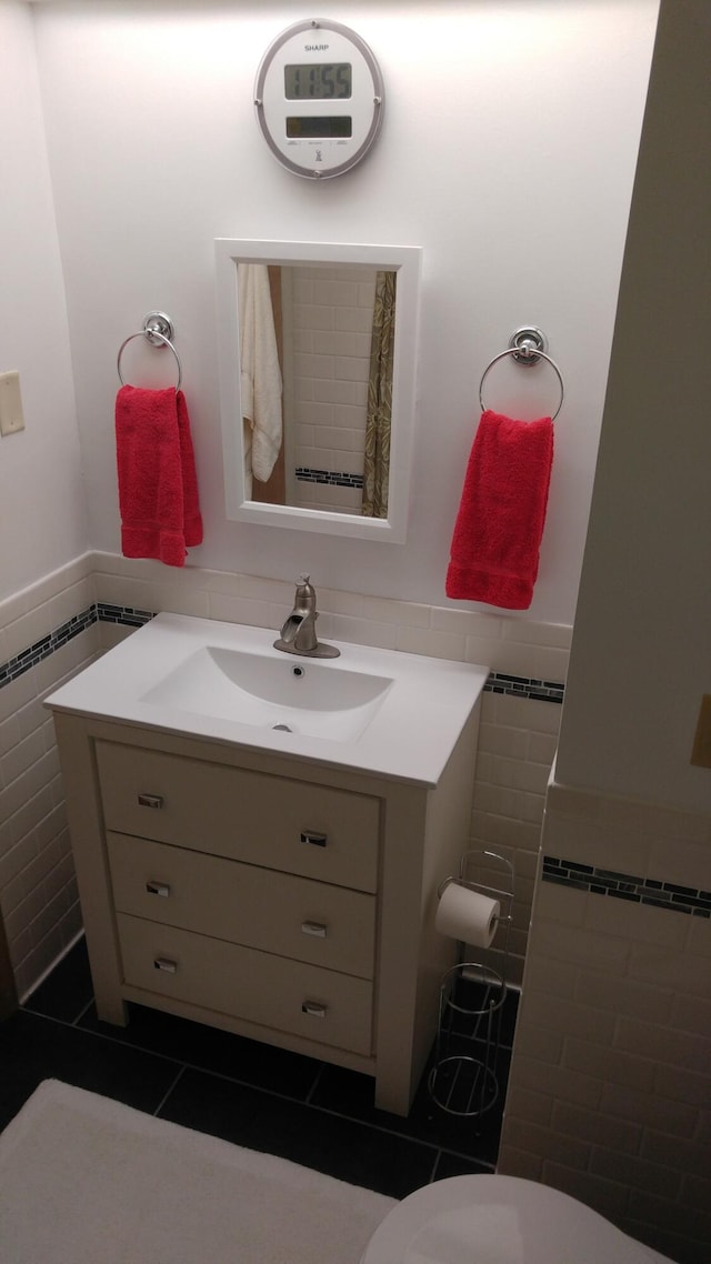 bathroom featuring tile patterned floors, tile walls, vanity, and a wainscoted wall