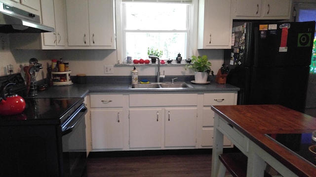 kitchen featuring white cabinets, a sink, dark countertops, under cabinet range hood, and black appliances