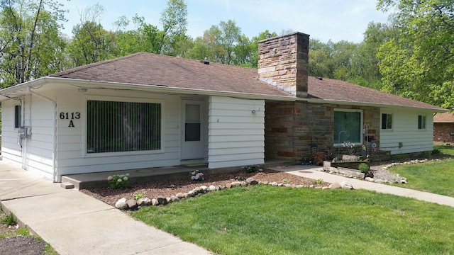 ranch-style house featuring roof with shingles, a chimney, and a front yard