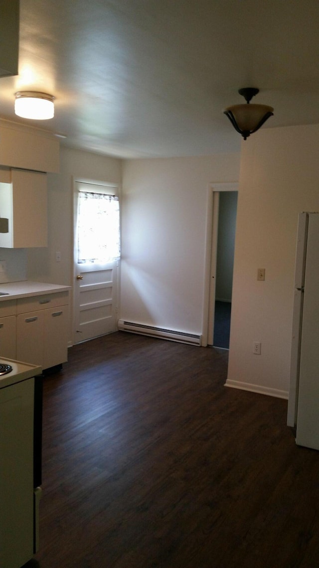 kitchen with dark wood-style flooring, white cabinets, freestanding refrigerator, and baseboard heating