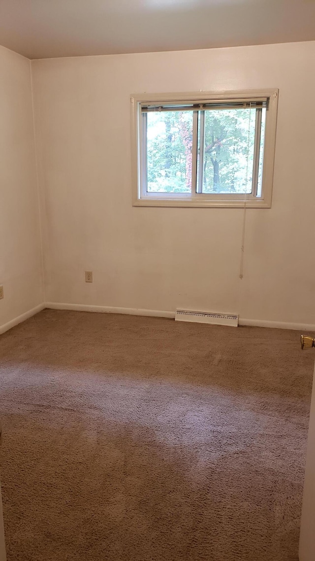 carpeted spare room featuring baseboards, visible vents, and a wealth of natural light