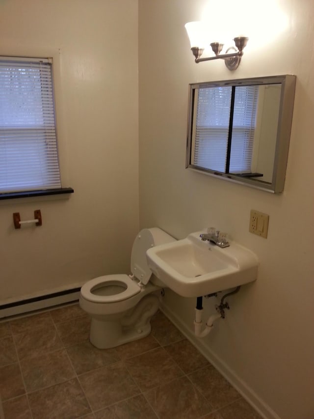 half bathroom featuring toilet, a baseboard radiator, baseboards, and a sink